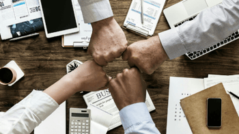 financial services teamwork, four people fist bumping over a desk