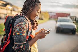 Rwandan woman after work using cell phone to text with Bridges to Prosperity using Mogli SMS from Salesforce